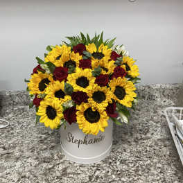 Bouquet of yellow sunflowers and red roses in a white hatbox