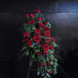 Tall standing spray of red roses arranged in a cascading shape on a black stand.