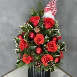 Christmas arrangement with red roses, ornaments, and a Santa hat