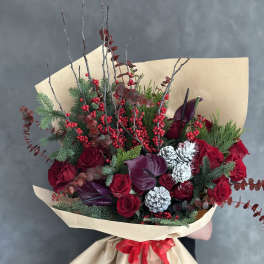 Bouquet of red roses with burgundy calla lilies and berries in kraft paper