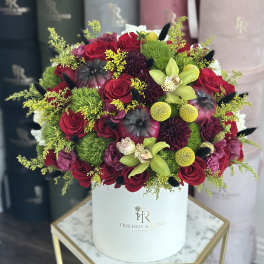 Round bouquet of red roses and green orchids in a white hat box