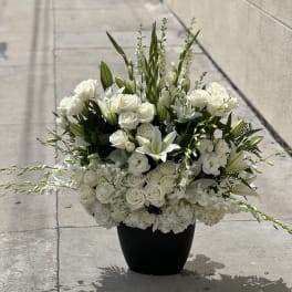 White roses and lilies arranged in a black vase