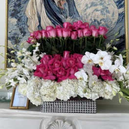 Pink roses and white orchids arranged in a decorative box