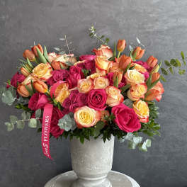 Bouquet of pink and peach roses in a gray urn vase