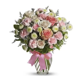 Pink and white rose bouquet in a glass vase with a pink ribbon