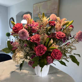 Large pink and peach floral arrangement in a white vase