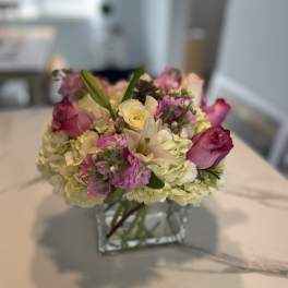 Pink and white flower arrangement in a square glass vase