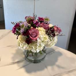 Pink roses and white hydrangeas in a glass vase with a heart pick