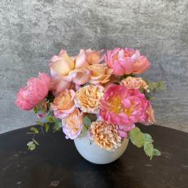 Pink and peach floral arrangement in a white vase