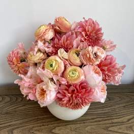 Pink and peach flowers arranged in a white vase