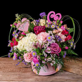Pink and purple mixed flower arrangement in a pink heart-shaped box