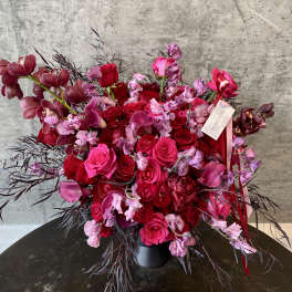 Bouquet of red and pink roses with orchids in a black vase