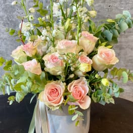 Pink roses and white flowers arranged in a gray vase with eucalyptus