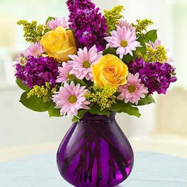 Yellow roses and pink daisies in a purple glass vase