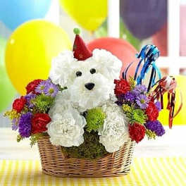 White teddy bear in a basket surrounded by colorful flowers and balloons