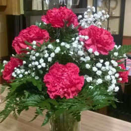 Pink carnations and white baby's breath in a clear glass vase