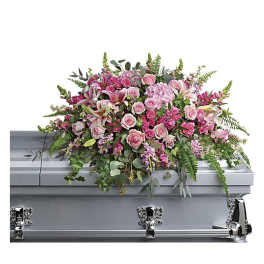 Pink floral casket spray with roses and lilies on a silver casket