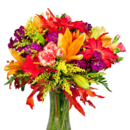 Bright mixed bouquet of lilies, gerbera daisies, and carnations in a glass vase