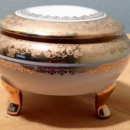 Decorative lidded metal bowl with ornate floral patterns on short feet