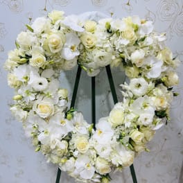 Heart-shaped white floral wreath on a stand
