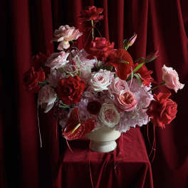 Red and pink rose arrangement in a white vase