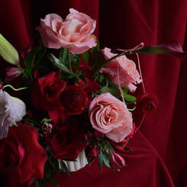 Bouquet of pink and red roses with a lily bud in a white vase