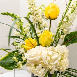 Yellow roses and white flowers arranged in a vase