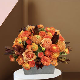 Orange and peach roses in a gray rectangular vase
