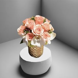 Peach roses and white orchids arranged in a gold vase