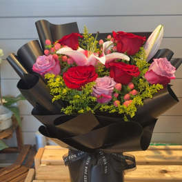 Bouquet of red and pink roses with lilies wrapped in black paper