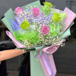 Bouquet of pink and green roses with baby's breath in pastel wrapping
