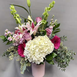 Tall pink and white mixed flower arrangement with hydrangea, lilies, and gerbera daisies in a pink vase
