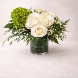 White roses and a green hydrangea in a glass vase