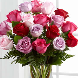 Bouquet of pink, red, and lavender roses in a clear glass vase
