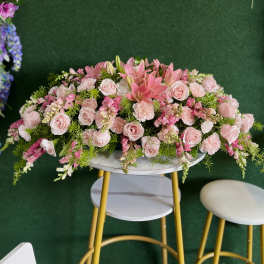 Large pink floral arrangement with roses and lilies on a round table