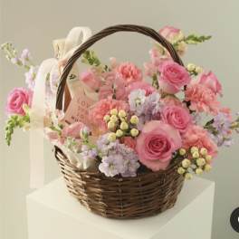 Pink and lavender flower basket in a wicker handle basket