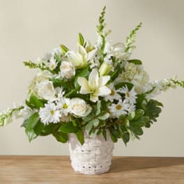 White lilies and daisies arranged in a white basket
