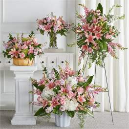 Pink lily and rose floral arrangements in vases and a basket