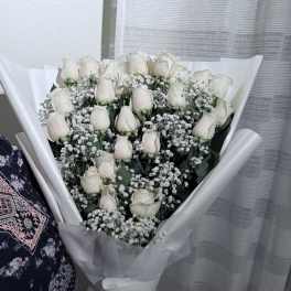 Bouquet of white roses and baby's breath wrapped in white paper
