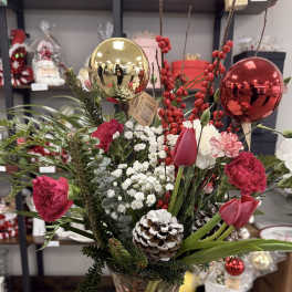 Holiday bouquet in a glass vase with red flowers, berries, and ornaments