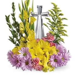 Yellow gladiolus and purple daisies arranged around a silver bottle