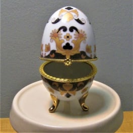 Decorative egg-shaped trinket box with gold trim on a round stand