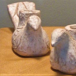 Two bird-shaped ceramic candle holders on a gold cloth