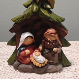 Nativity figurine under a Christmas tree with Mary, Joseph, and baby Jesus