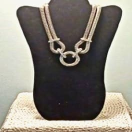 Silver necklace displayed on a black bust stand
