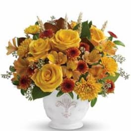 Yellow roses and orange mums arranged in a white vase