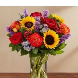 Bouquet of red roses and sunflowers in a clear glass vase