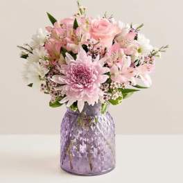 Pink and white mixed bouquet in a purple glass vase