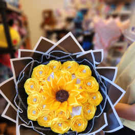 Yellow rose bouquet with a sunflower center and decorative wrap