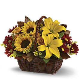 Basket arrangement with yellow lilies, sunflowers, and red daisies